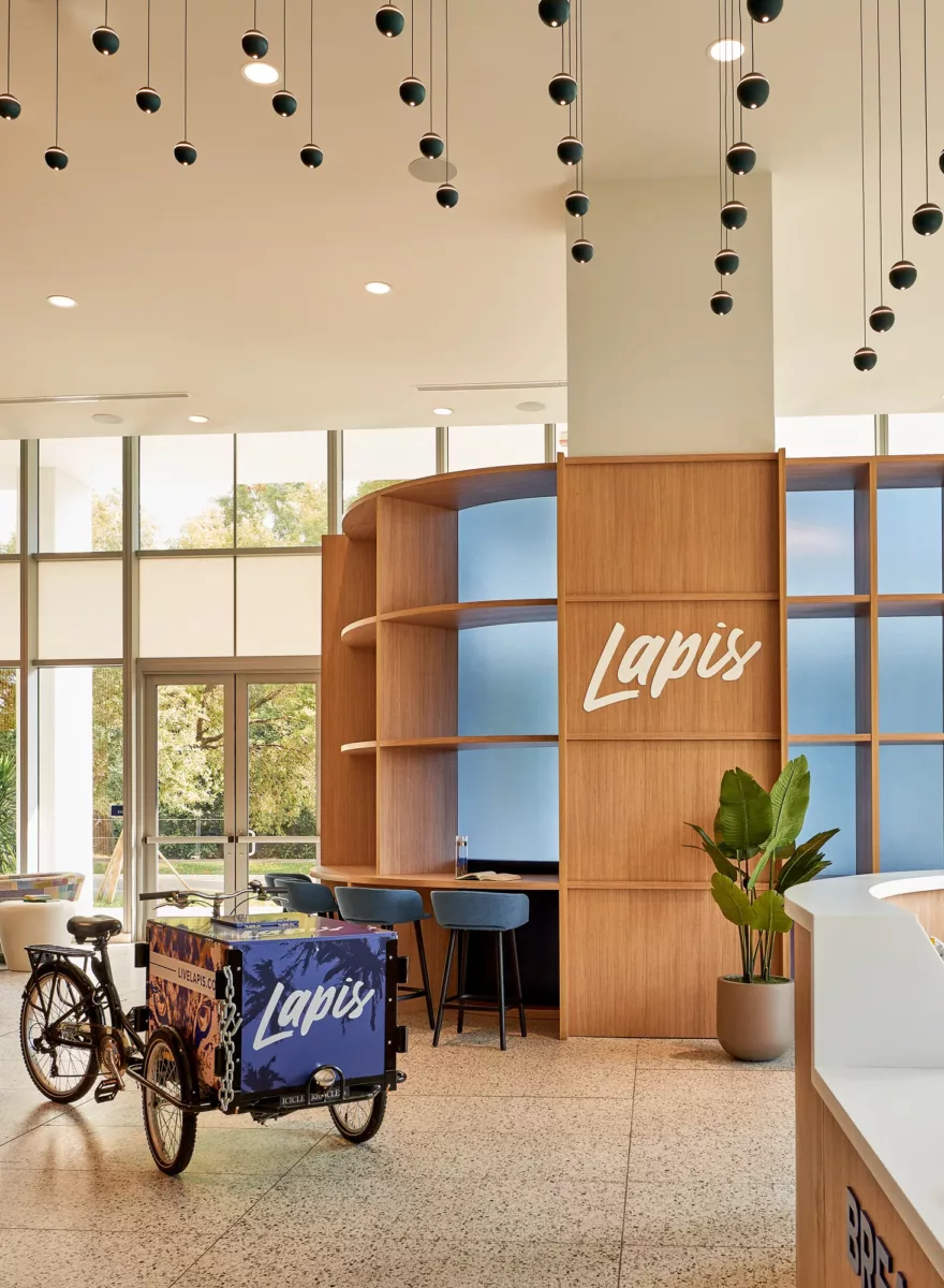 Apartment lobby featuring “Lapis” signage, wood shelving, bike display, and seating.