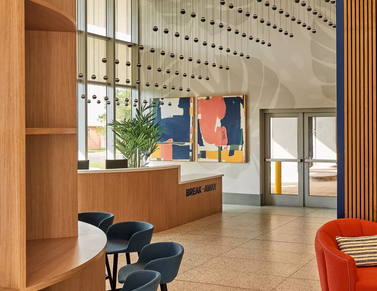 Apartment lobby with wood accents, abstract art, pendant lights, and seating area.
