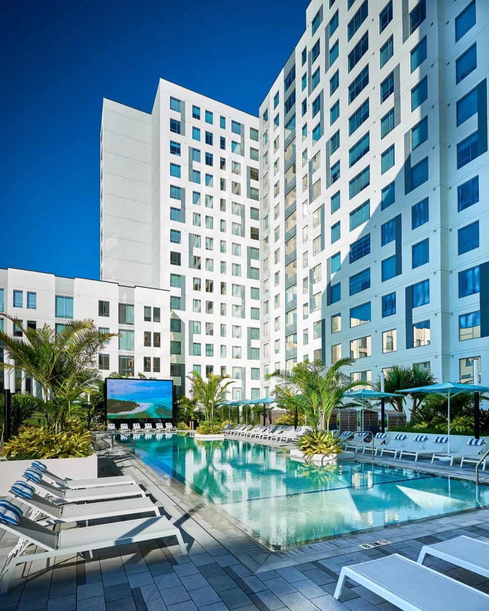 Outdoor pool courtyard surrounded by modern apartment buildings and lounge chairs.