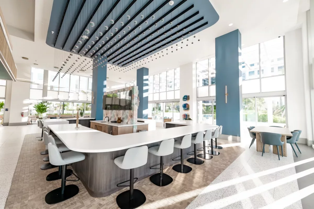 Modern resident lounge with large communal table, bar seating, and floor-to-ceiling windows