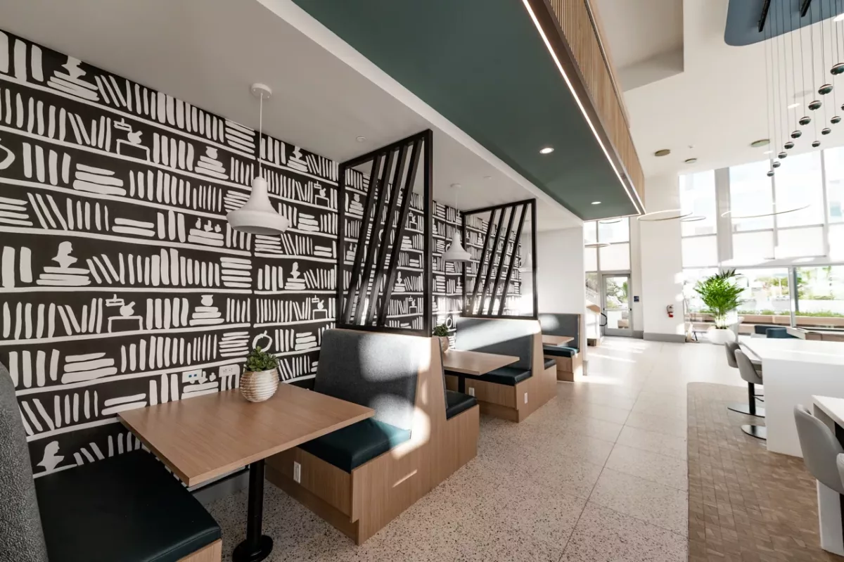 Resident dining booths with patterned wall, pendant lights, and modern wood tables
