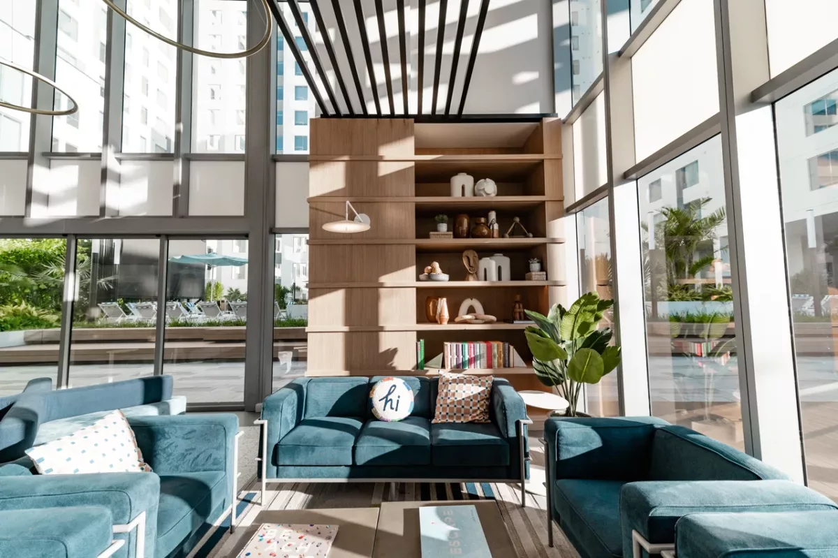 Sunlit lounge seating with blue sofas, decorative shelving, and courtyard views