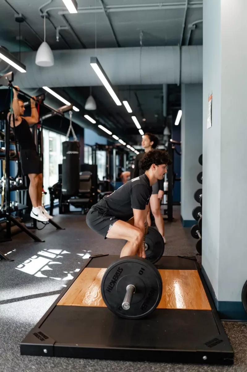 Fitness center with residents weightlifting, mirrors, and professional gym equipment.