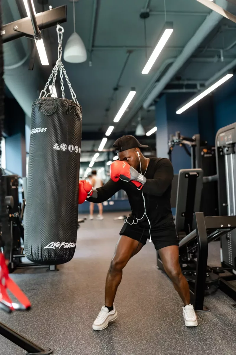 Resident boxing a hanging heavy bag in a fully equipped indoor gym.