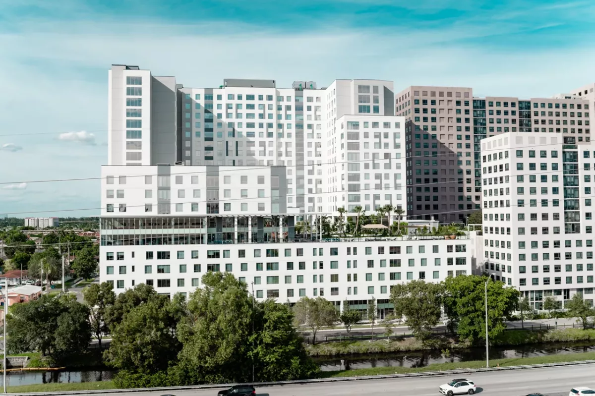 Multi‑building apartment complex with white façades, rooftop terrace, and landscaped surroundings.