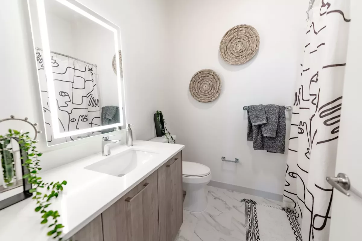 Contemporary bathroom with vanity, illuminated mirror, toilet, and patterned shower curtain