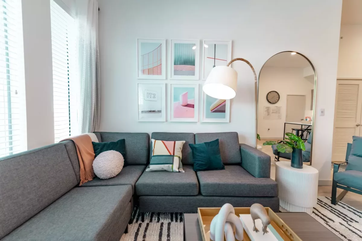 Modern living room with gray sectional sofa, abstract art, floor lamp, and tray table