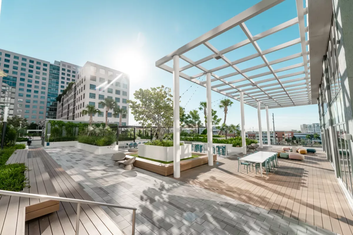 Rooftop terrace with pergola seating, planters, and city views in bright daylight