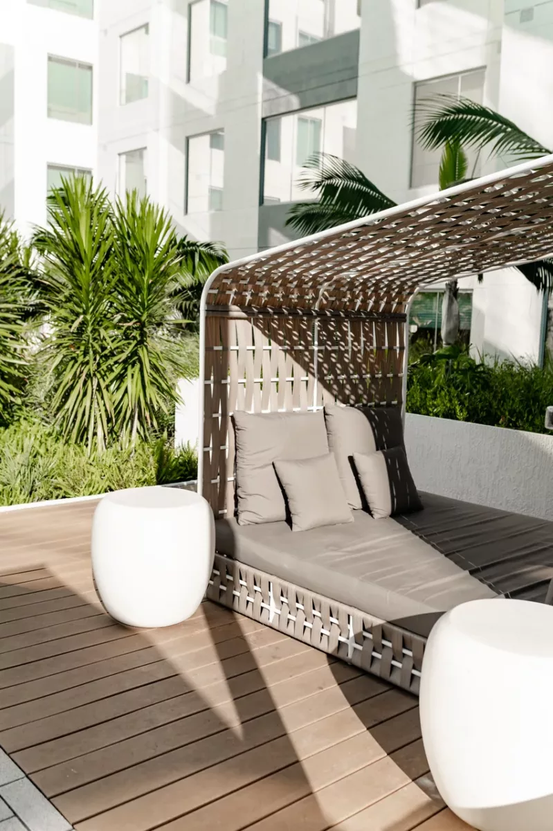Private outdoor cabana daybed with cushions surrounded by greenery