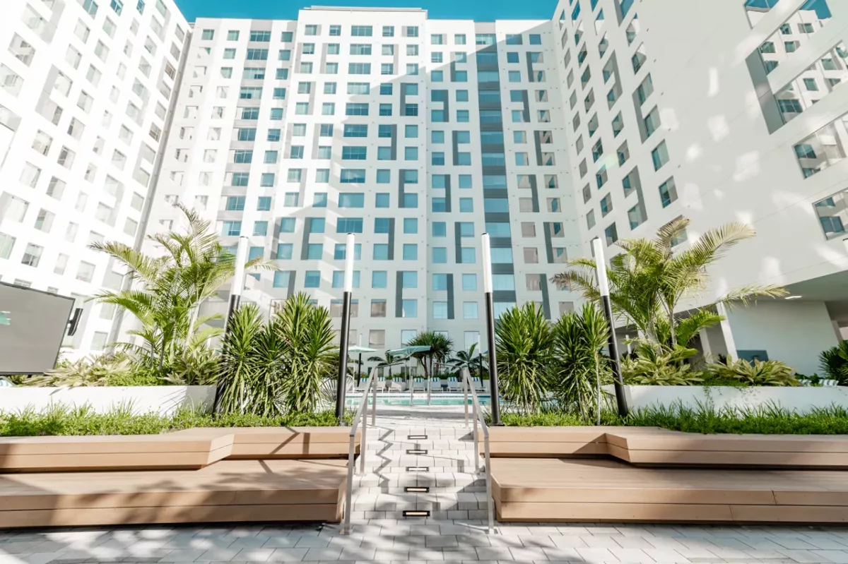 Landscaped courtyard with stepped seating, palm trees, and mid-rise apartment buildings