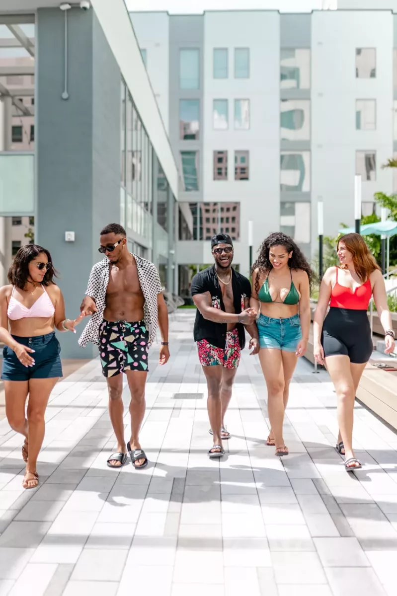 Group of residents walking through a pool courtyard surrounded by modern apartment buildings.